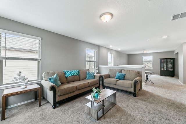 living room with a wealth of natural light, carpet, visible vents, and baseboards