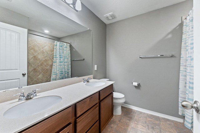 full bathroom featuring double vanity, a sink, toilet, and baseboards