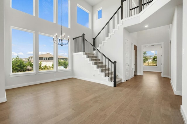 foyer entrance with baseboards, stairway, wood finished floors, and a healthy amount of sunlight