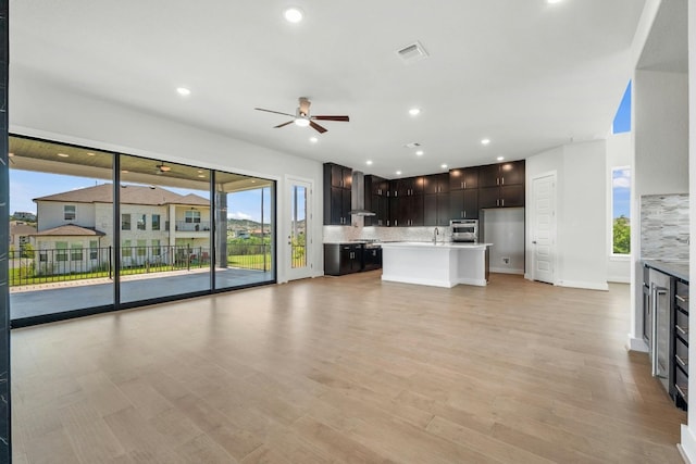 unfurnished living room with light wood finished floors, visible vents, a ceiling fan, a sink, and recessed lighting