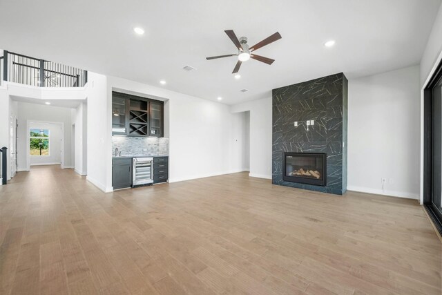 unfurnished living room with ceiling fan, a fireplace, light hardwood / wood-style floors, and wine cooler