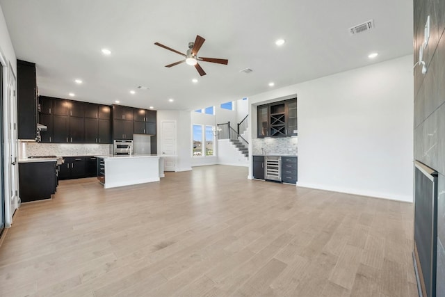 unfurnished living room with visible vents, a ceiling fan, light wood-style flooring, stairs, and recessed lighting