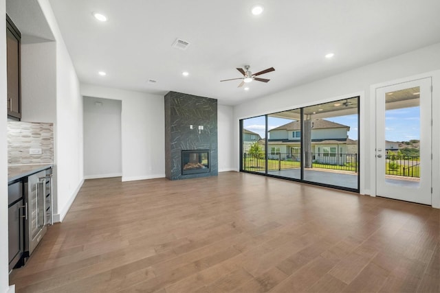 unfurnished living room featuring visible vents, beverage cooler, light wood finished floors, and a high end fireplace