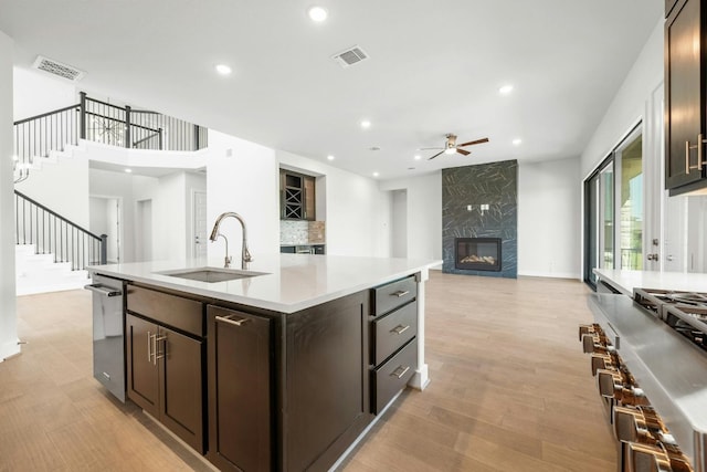 kitchen with ceiling fan, backsplash, light hardwood / wood-style floors, dishwasher, and a fireplace