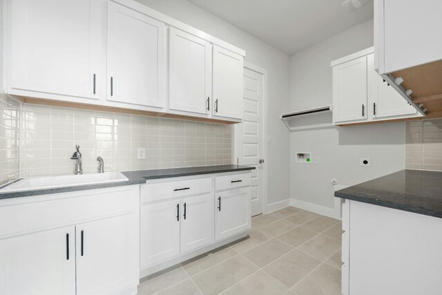 kitchen featuring light tile patterned floors, decorative backsplash, white cabinets, a sink, and baseboards