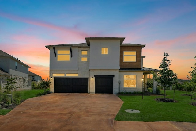 contemporary home featuring a garage, concrete driveway, metal roof, a standing seam roof, and a yard