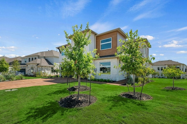 back of property with a residential view, a standing seam roof, driveway, and a lawn