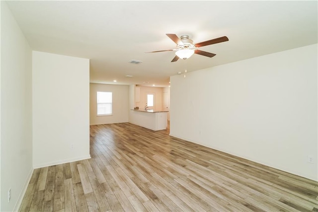 empty room with ceiling fan and light hardwood / wood-style flooring