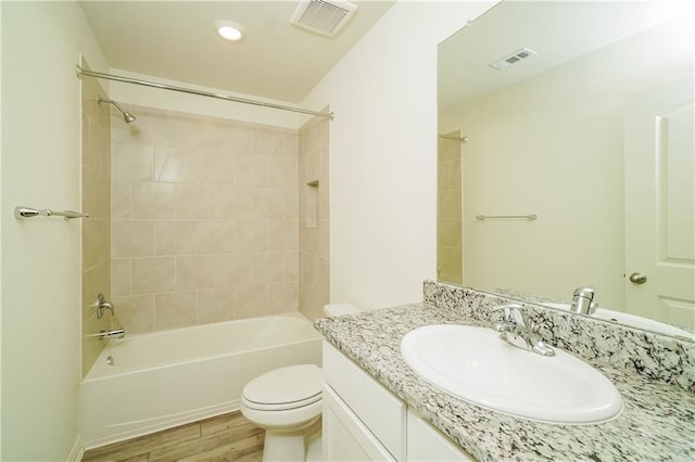 full bathroom with hardwood / wood-style floors, vanity, toilet, and tiled shower / bath