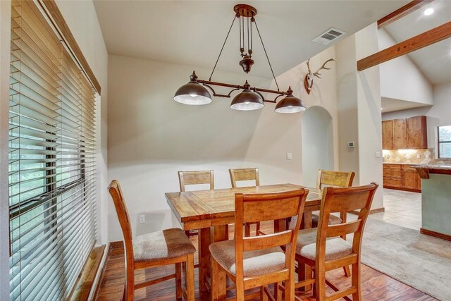 dining space with vaulted ceiling and light hardwood / wood-style flooring