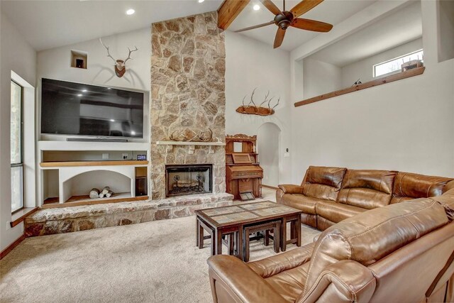 living room with a stone fireplace, carpet, ceiling fan, beam ceiling, and built in shelves