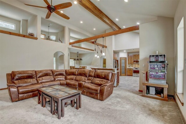 carpeted living room with beamed ceiling, ceiling fan, and a high ceiling