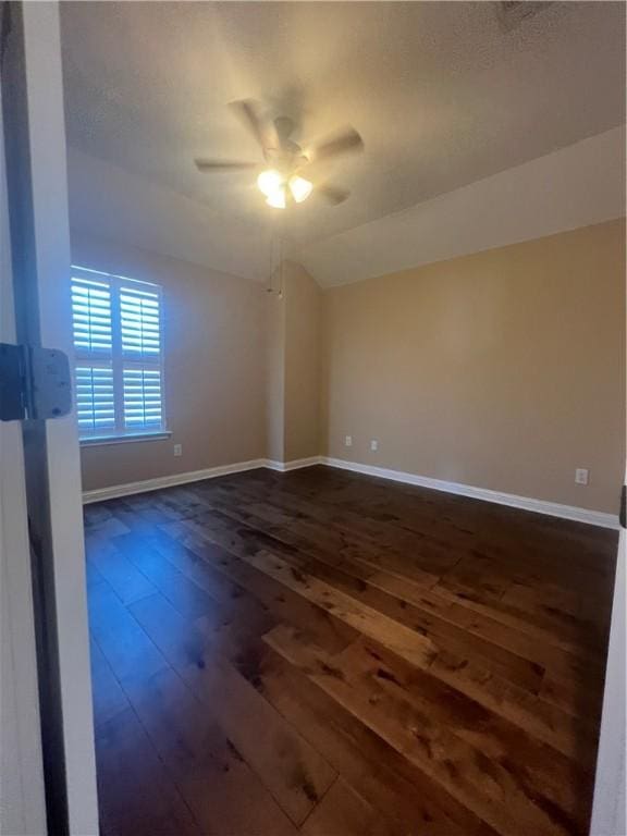 empty room featuring ceiling fan, dark hardwood / wood-style floors, and vaulted ceiling