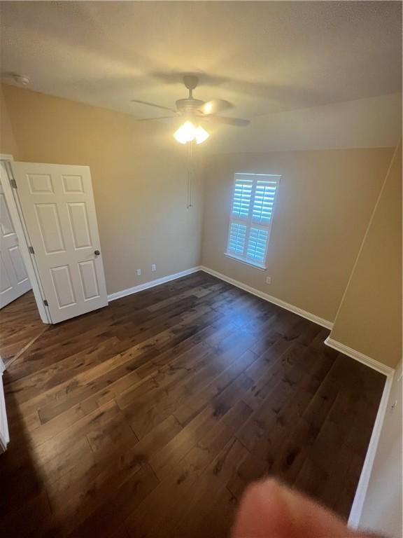 unfurnished room featuring ceiling fan and dark wood-type flooring