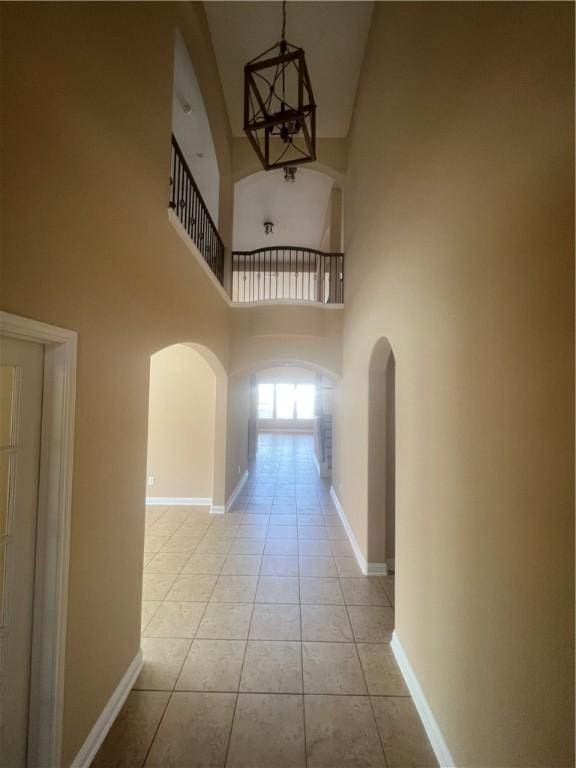 hallway with light tile patterned flooring, a high ceiling, and a notable chandelier