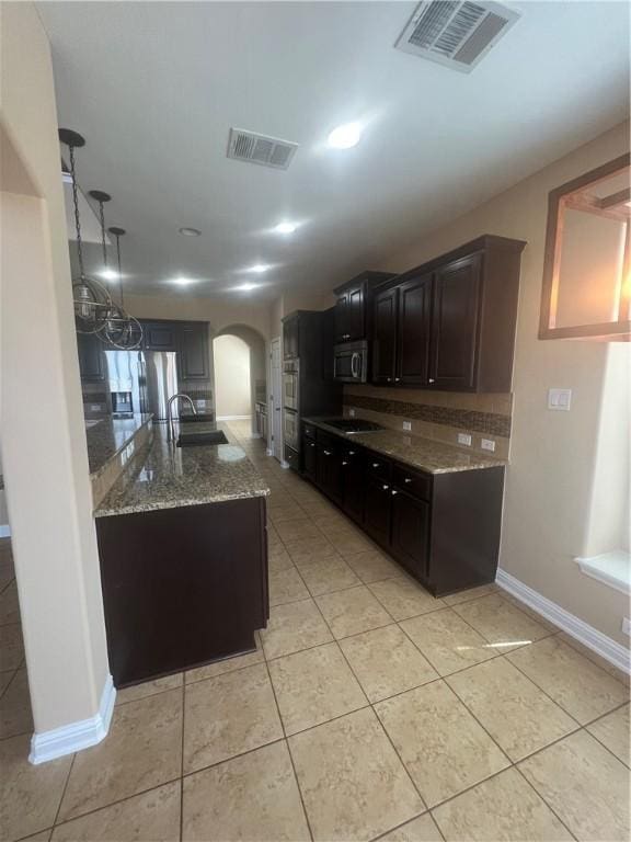 kitchen with backsplash, sink, light tile patterned floors, light stone counters, and stainless steel appliances