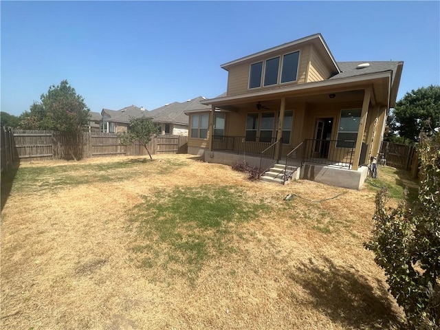 rear view of house with ceiling fan and a yard