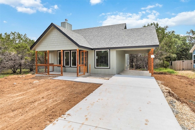 back of house with covered porch and a carport