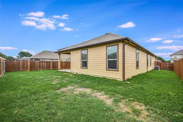 rear view of property with central air condition unit and a lawn