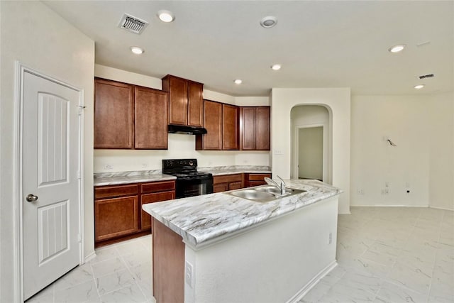 kitchen featuring light stone countertops, electric range, a kitchen island with sink, and sink