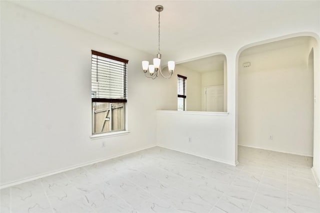 empty room with plenty of natural light and a chandelier