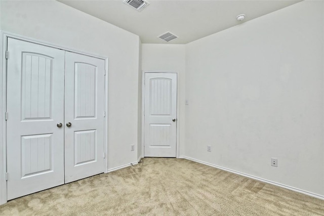 unfurnished bedroom featuring light carpet and a closet