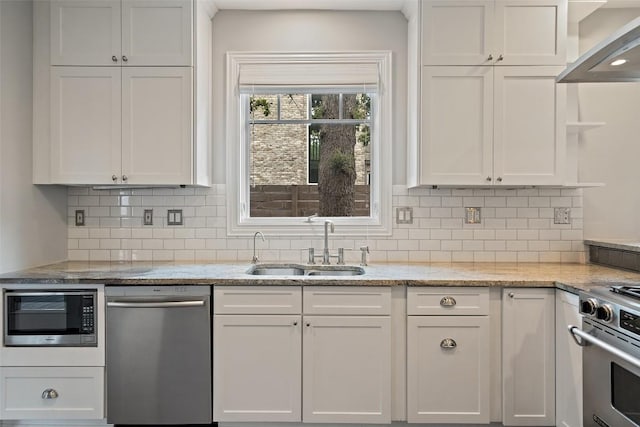 kitchen with light stone counters, white cabinetry, backsplash, and appliances with stainless steel finishes