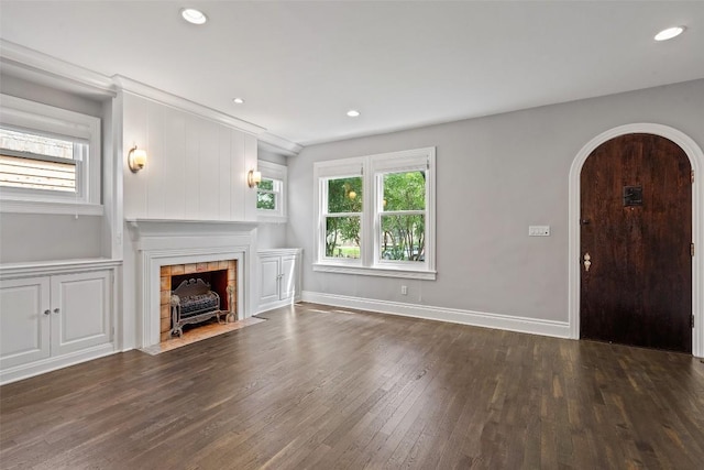 unfurnished living room with dark hardwood / wood-style flooring and a tiled fireplace