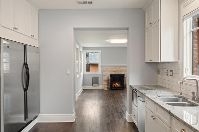 kitchen with white cabinets, sink, light stone countertops, and stainless steel appliances