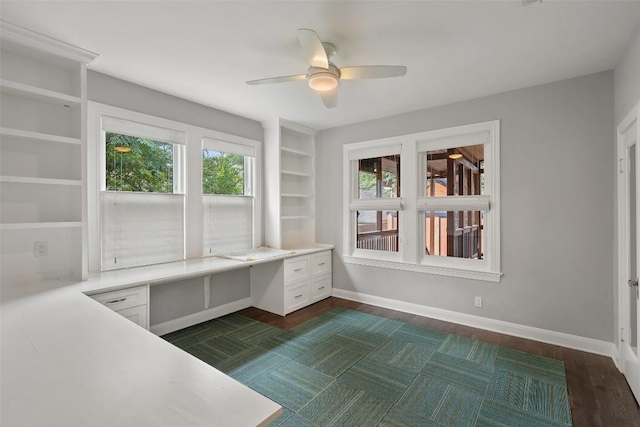 unfurnished office featuring ceiling fan, a healthy amount of sunlight, and built in desk