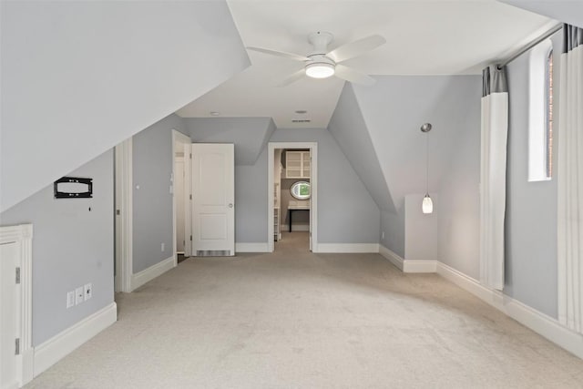 additional living space with ceiling fan, light colored carpet, a healthy amount of sunlight, and lofted ceiling