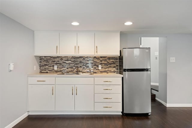 kitchen featuring backsplash, stainless steel fridge, sink, and white cabinets