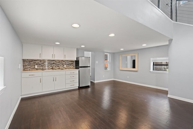 kitchen featuring white cabinetry, sink, dark hardwood / wood-style floors, stainless steel fridge, and decorative backsplash