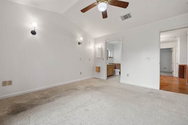 unfurnished bedroom featuring ensuite bath, light carpet, ceiling fan, and lofted ceiling