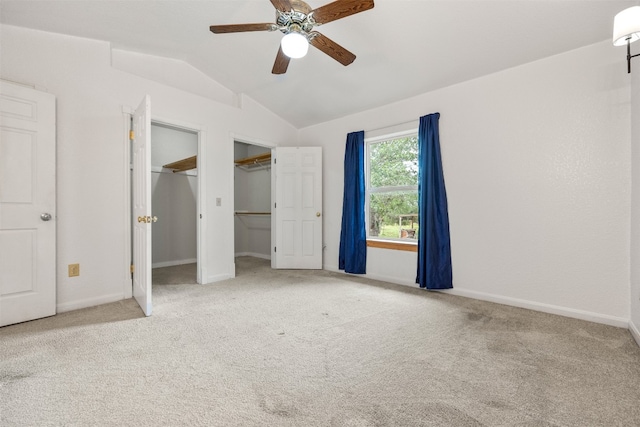 unfurnished bedroom with multiple closets, ceiling fan, light colored carpet, and lofted ceiling