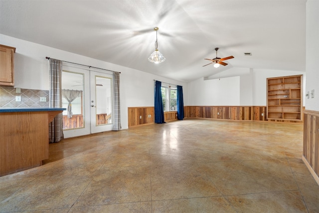 unfurnished room featuring french doors, ceiling fan, concrete floors, lofted ceiling, and wood walls