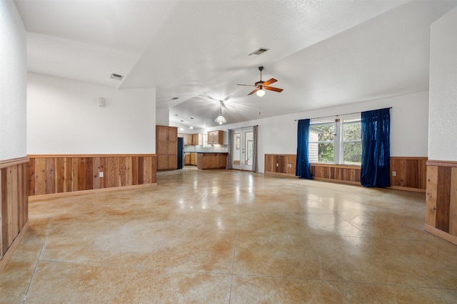 unfurnished living room featuring ceiling fan, lofted ceiling, a textured ceiling, and wooden walls