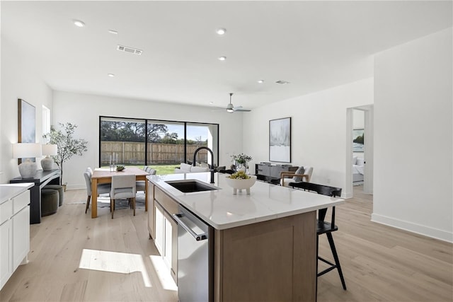 kitchen featuring dishwasher, a kitchen island with sink, sink, light hardwood / wood-style floors, and white cabinetry