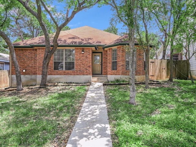 view of front of home with brick siding, a shingled roof, and fence