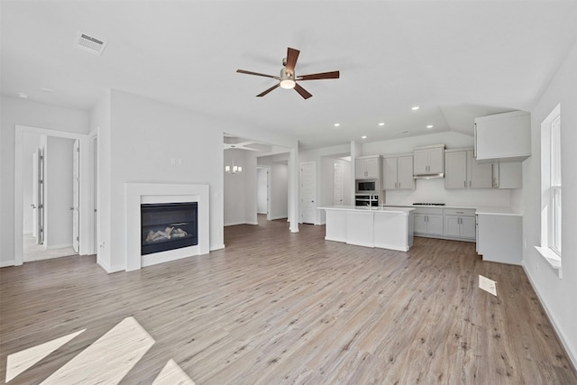 unfurnished living room featuring ceiling fan, light wood-type flooring, and lofted ceiling