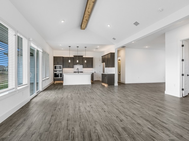 unfurnished living room with sink, dark wood-type flooring, and lofted ceiling with beams