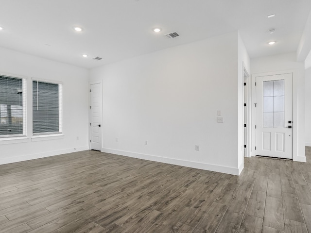 unfurnished room featuring visible vents, baseboards, and wood finished floors