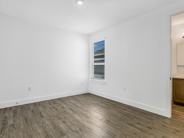 empty room featuring baseboards and dark wood-type flooring