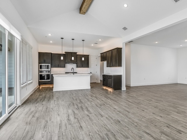 kitchen featuring lofted ceiling with beams, sink, an island with sink, and light hardwood / wood-style floors