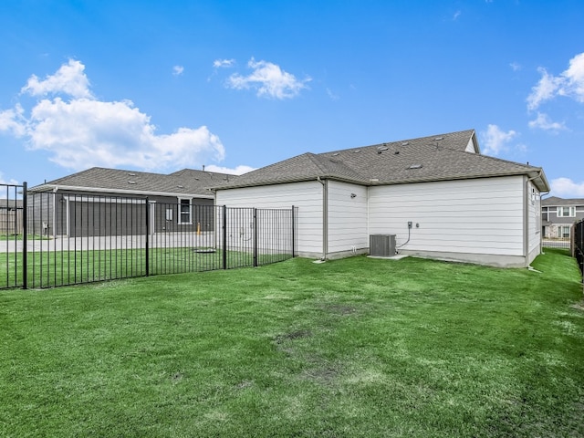 rear view of house with a yard, central AC, fence, and roof with shingles