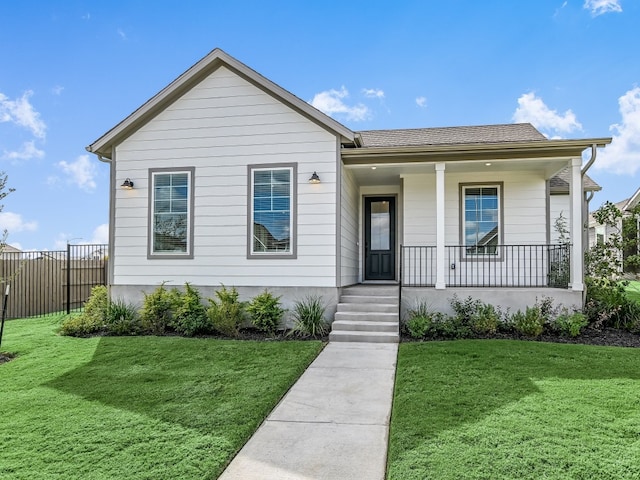 view of front facade featuring a front yard, covered porch, and fence