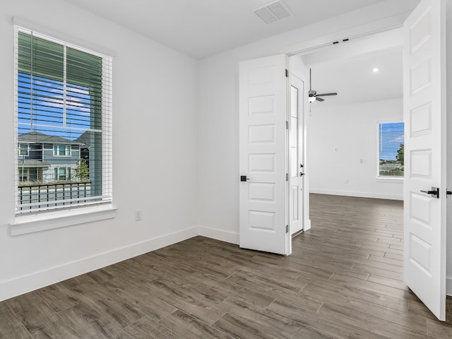 empty room with baseboards, visible vents, dark wood finished floors, and a ceiling fan