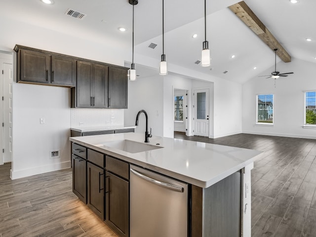 kitchen featuring an island with sink, open floor plan, hanging light fixtures, stainless steel dishwasher, and a sink