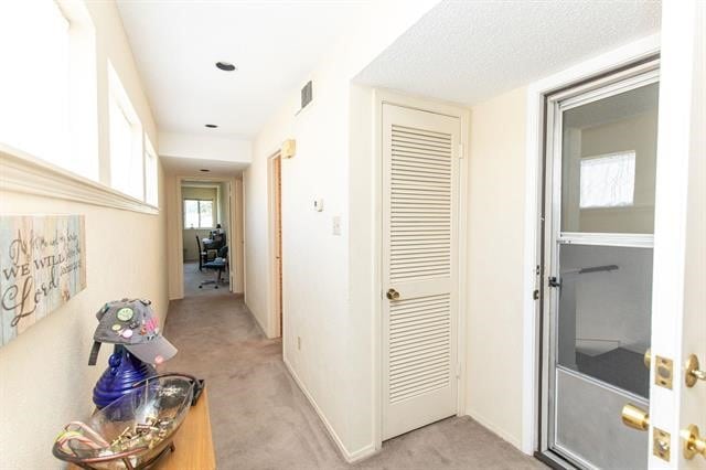 hall with light carpet and a textured ceiling