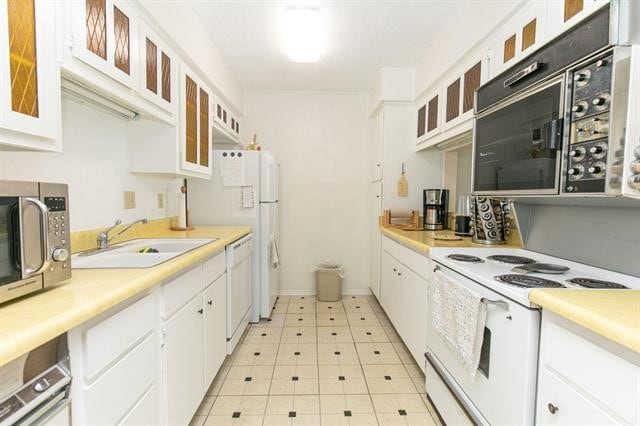 kitchen featuring white appliances, sink, light tile flooring, and white cabinetry